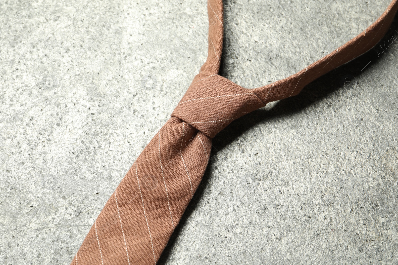 Photo of One striped necktie on grey textured background, top view