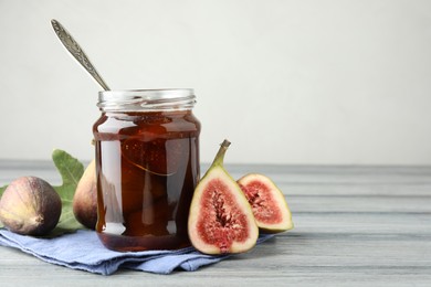 Photo of Jar of tasty sweet jam and fresh figs on grey table, space for text