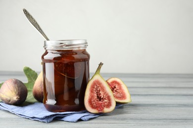 Jar of tasty sweet jam and fresh figs on grey table, space for text