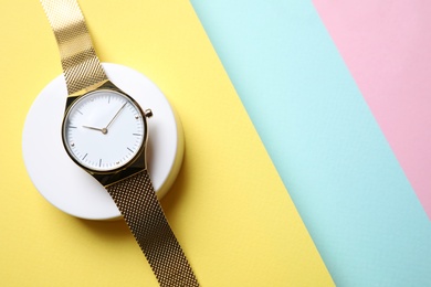 Stylish golden wristwatch on color background, top view. Space for text