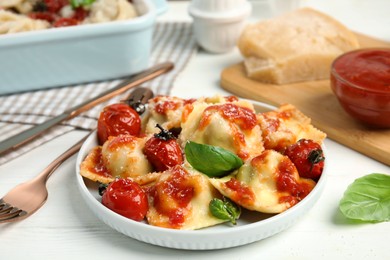 Tasty ravioli with tomato sauce served on white table