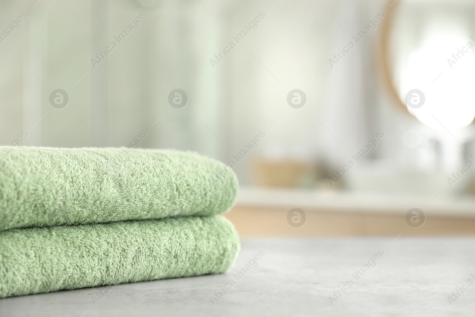 Photo of Stack of clean towels on table in bathroom. Space for text