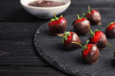 Photo of Slate plate with chocolate covered strawberries on table, closeup