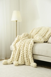 Photo of Knitted merino wool plaid on sofa in room