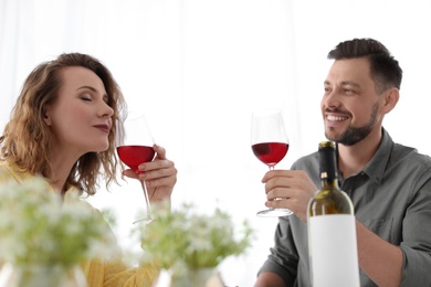 Young couple with glasses of delicious wine indoors