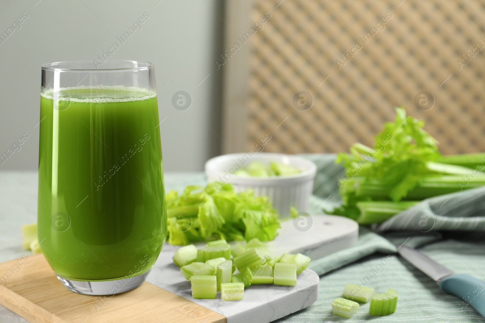 Photo of Glass of delicious celery juice and vegetables on wooden board, closeup. Space for text