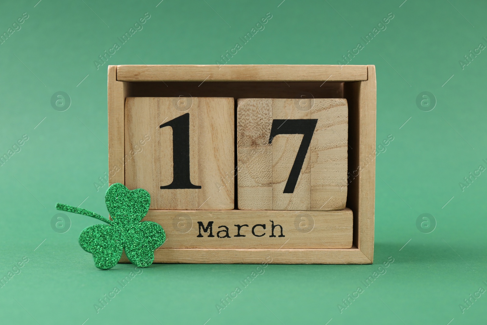 Photo of St. Patrick's day - 17th of March. Block calendar and decorative clover leaf on green background