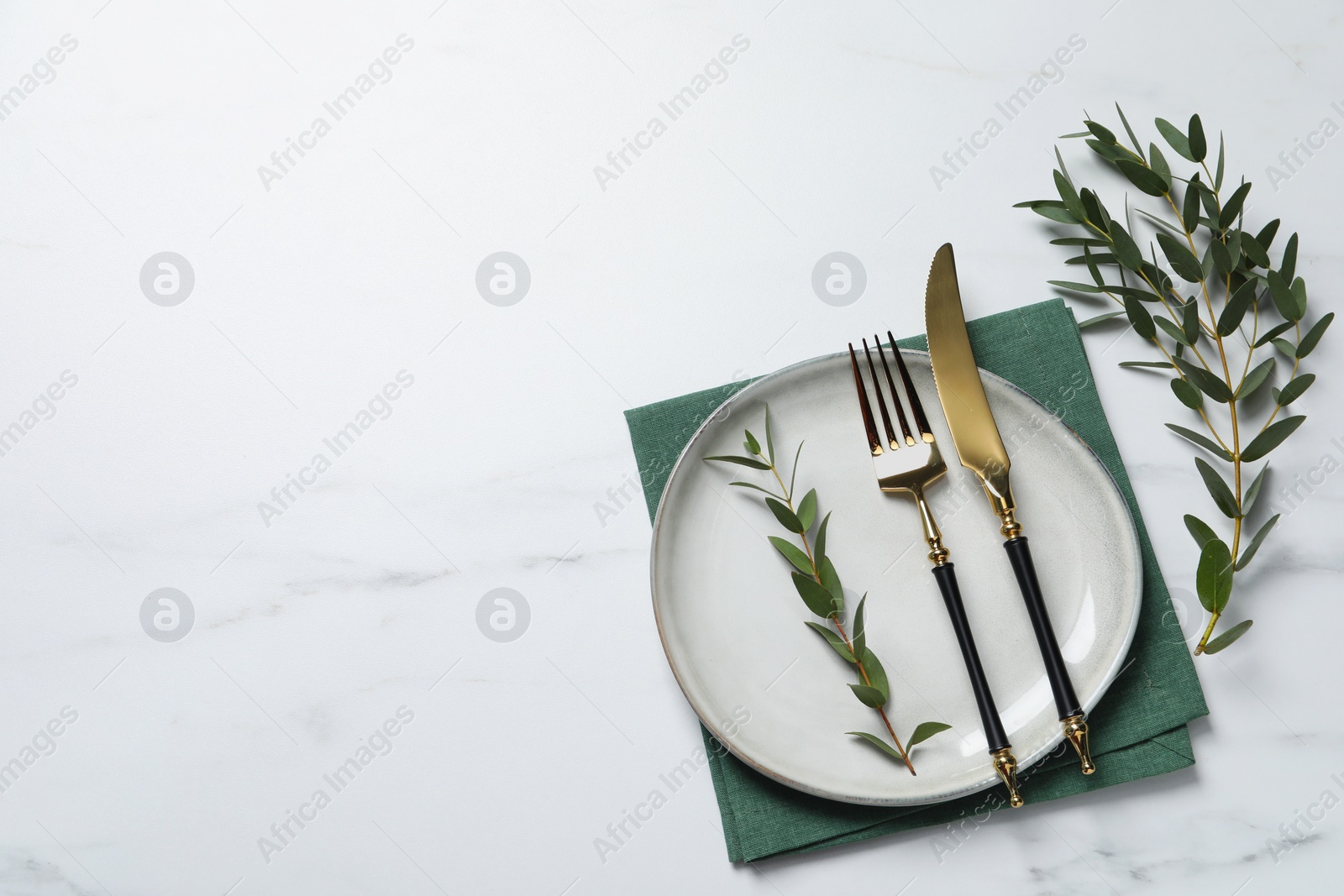 Photo of Stylish setting with cutlery and eucalyptus leaves on white marble table, flat lay. Space for text