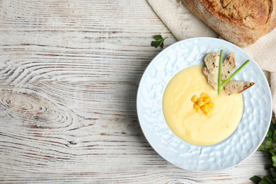 Photo of Delicious corn cream soup served on white wooden table, flat lay. Space for text