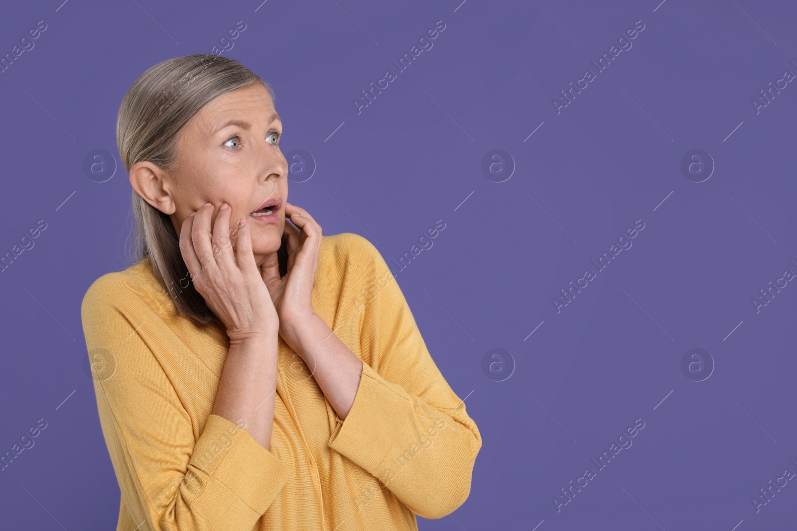 Photo of Portrait of surprised senior woman on violet background, space for text