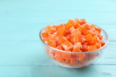 Photo of Frozen carrots on light blue wooden table, closeup. Vegetable preservation