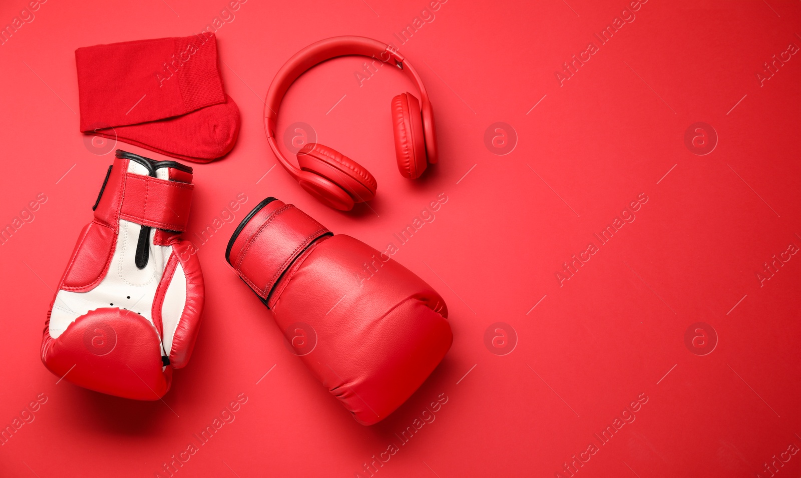 Photo of Sports equipment. Boxing gloves, headphones and socks on red background, flat lay. Space for text