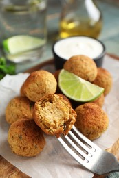 Photo of Delicious falafel balls with lime on wooden board, closeup