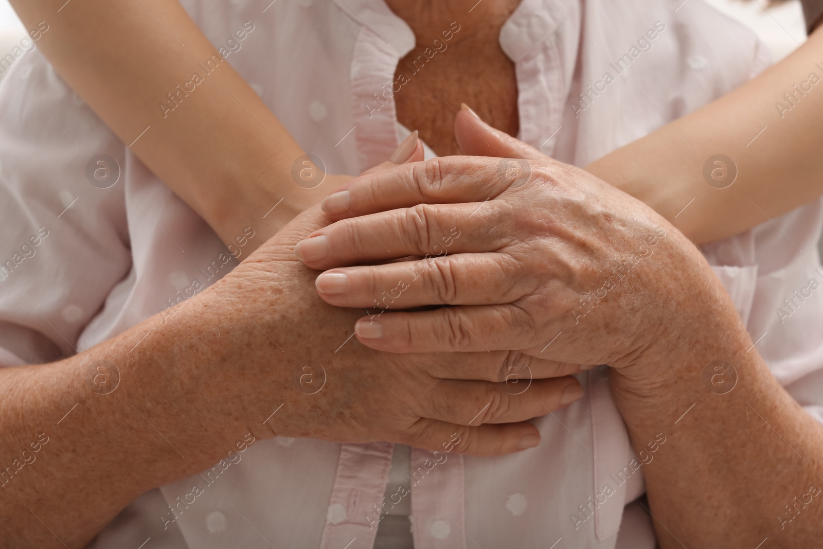 Photo of Young and elderly women hugging, closeup view