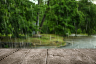 Image of Empty wooden table outdoors on rainy day