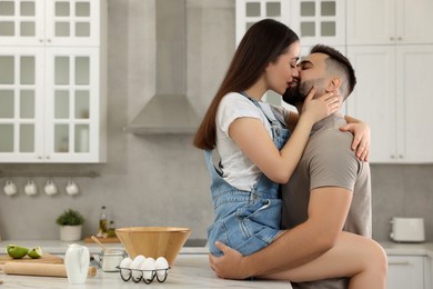 Photo of Affectionate young couple kissing in kitchen. Space for text