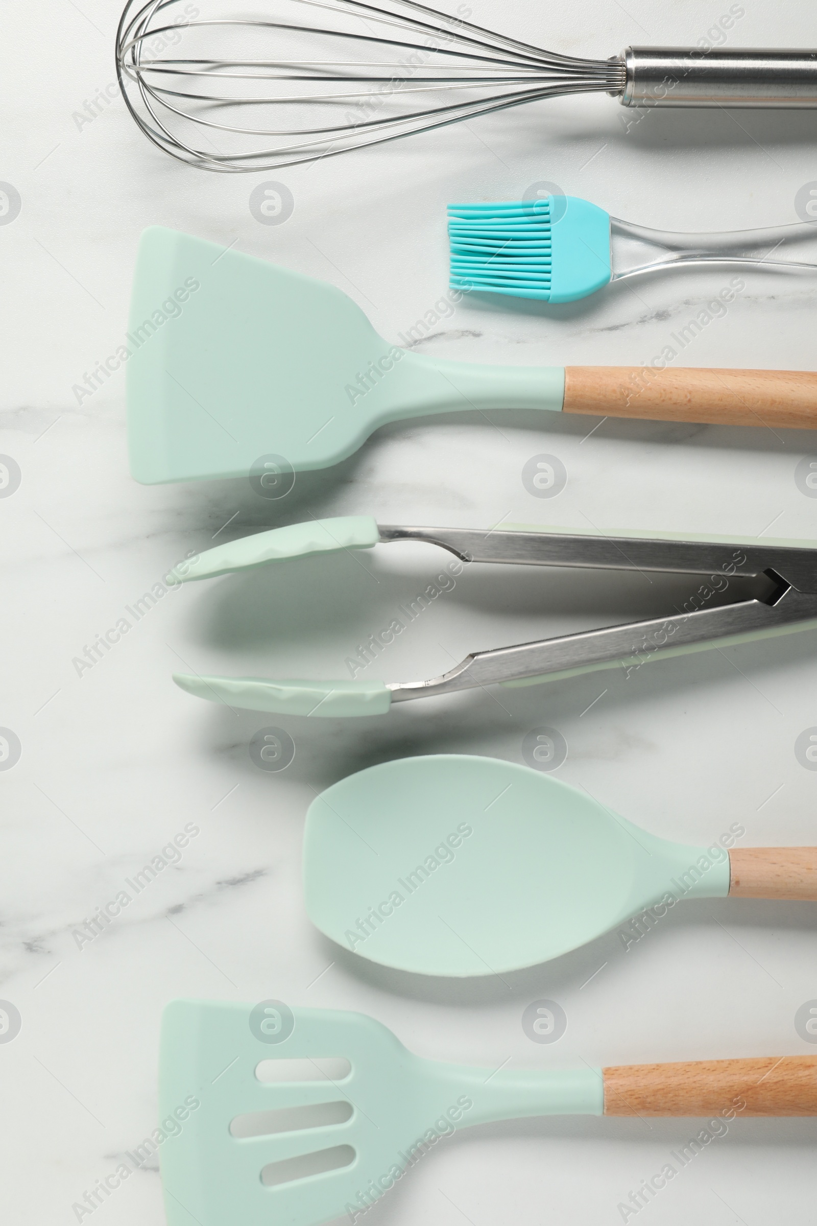 Photo of Different spatulas and other kitchen utensils on light marble table, flat lay