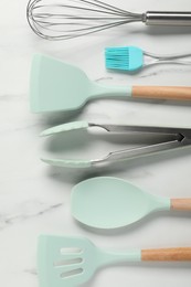 Photo of Different spatulas and other kitchen utensils on light marble table, flat lay