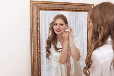 Photo of Young beautiful woman near mirror in makeup room