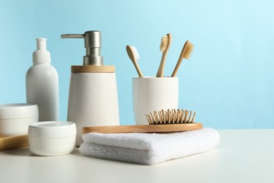 Different bath accessories on white table against light blue background