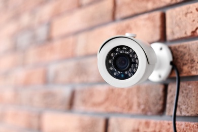 Photo of Modern security CCTV camera on brick wall