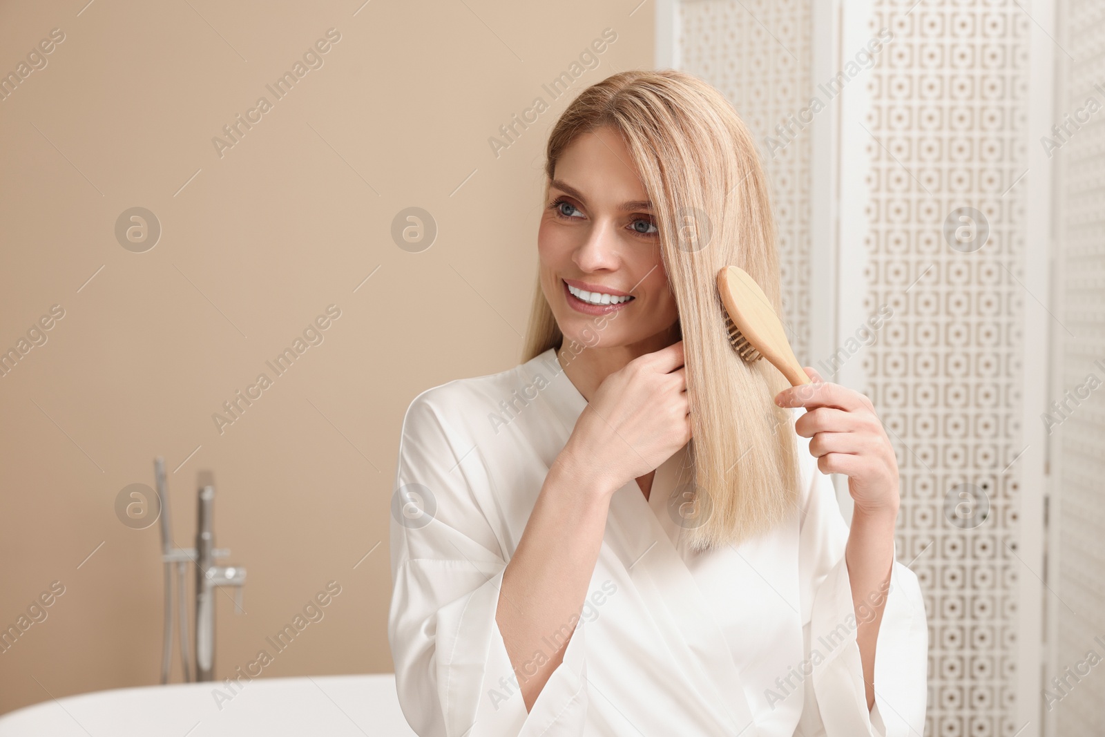 Photo of Beautiful woman brushing her hair in bathroom