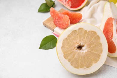 Photo of Different tasty pomelo fruits on white textured table, closeup. Space for text