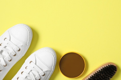 Flat lay composition with stylish footwear and shoe care accessories on yellow background, space for text