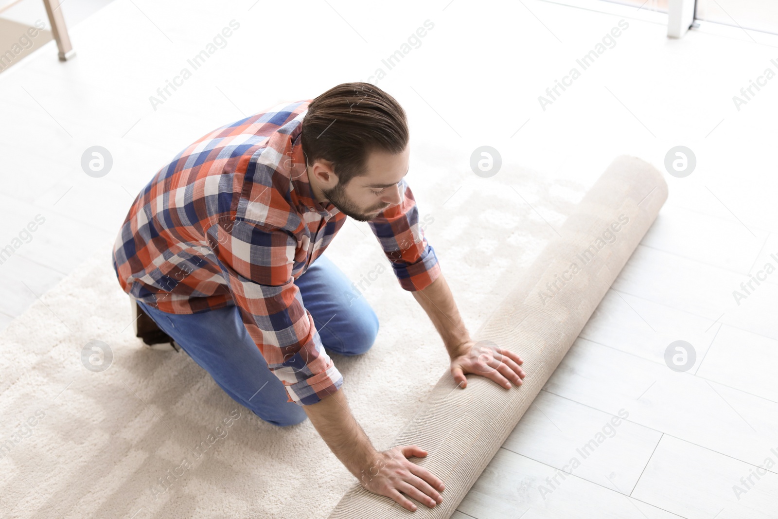 Photo of Man rolling out new carpet flooring in room