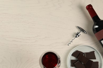 Photo of Flat lay composition with tasty red wine and chocolate on white wooden table. Space for text