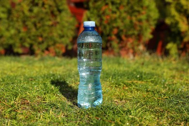 Photo of Plastic bottle of water on green grass outdoors