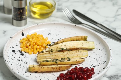Photo of Baked white carrot with sweet corn and pomegranate seeds on marble table, closeup