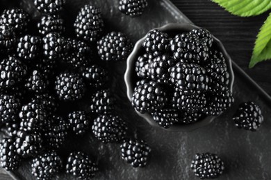 Fresh ripe blackberries and leaves on black board, flat lay