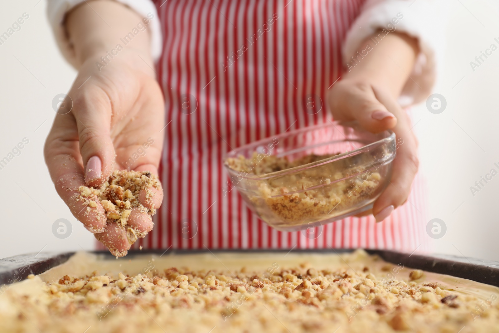 Photo of Making delicious baklava. Woman adding chopped nuts to dough, closeup