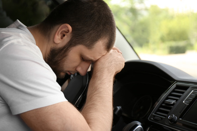 Photo of Tired man sleeping on steering wheel in his car