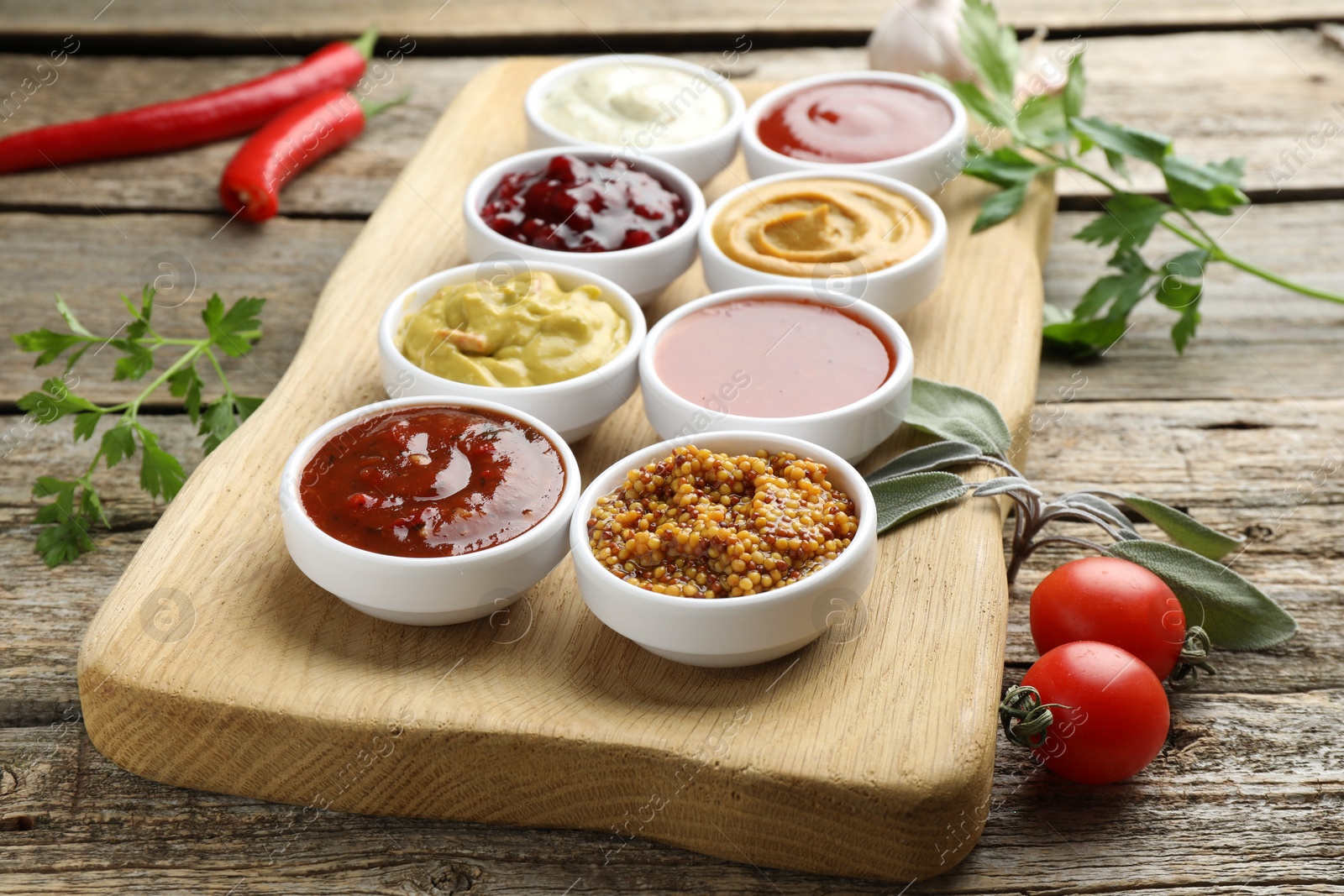 Photo of Different tasty sauces in bowls and ingredients on wooden table