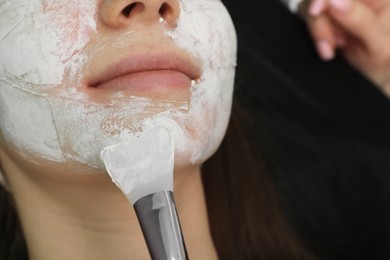 Photo of Cosmetologist applying mask on woman's face, closeup