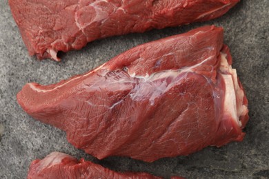 Pieces of raw beef meat on grey table, flat lay