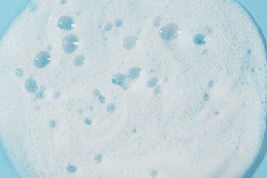 Photo of Sample of cleansing foam on light blue background, closeup. Cosmetic product