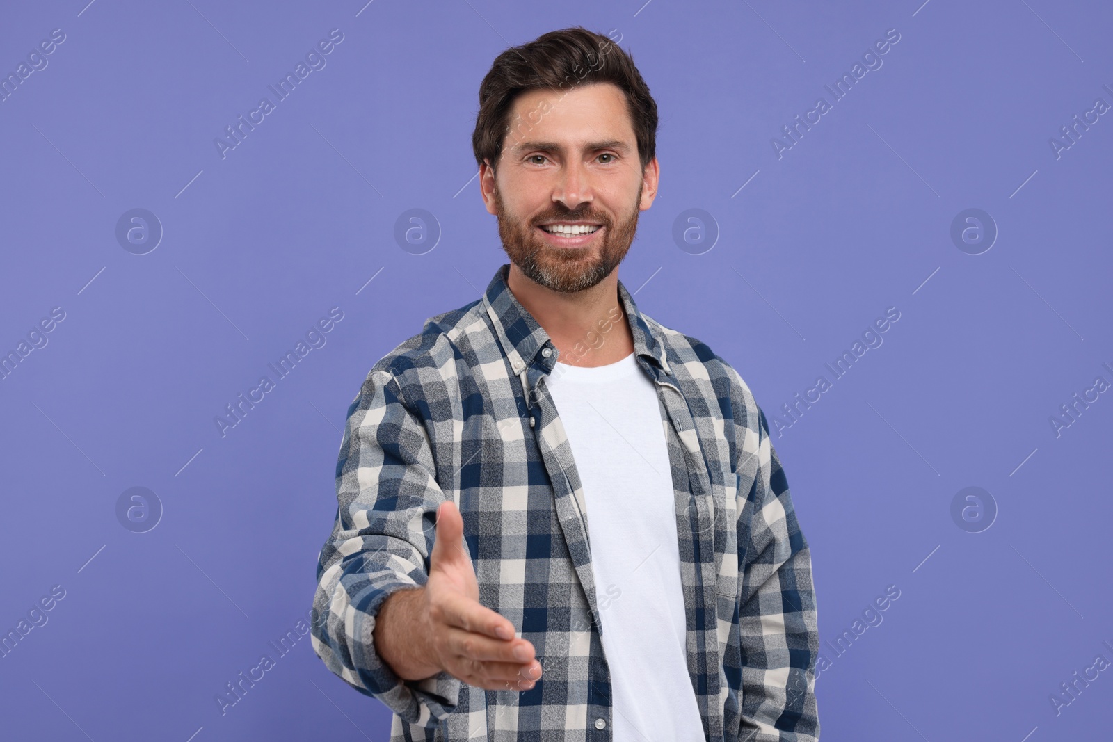 Photo of Happy man welcoming and offering handshake on purple background