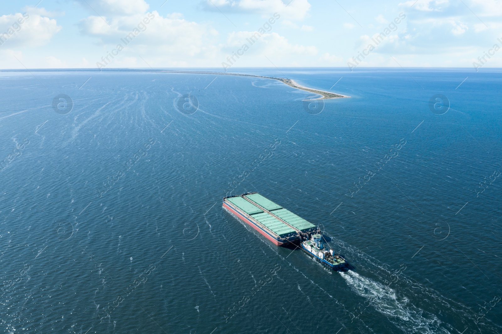 Image of Tugboat pulling barge with cargo by water,  aerial view