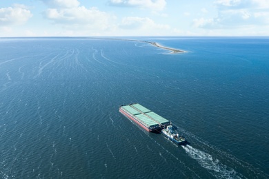 Tugboat pulling barge with cargo by water,  aerial view