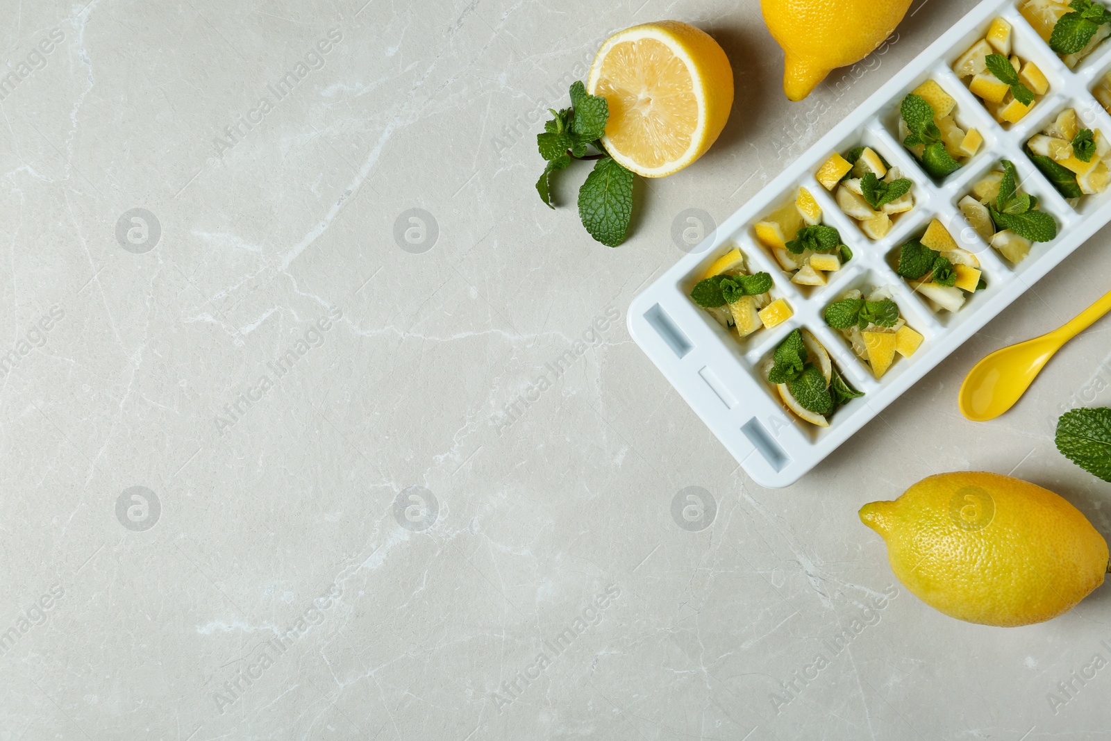 Photo of Ice cube tray with mint and lemon on grey background, top view. Space for text