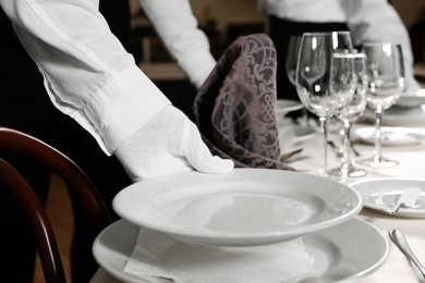 People setting table during professional butler courses in restaurant, closeup