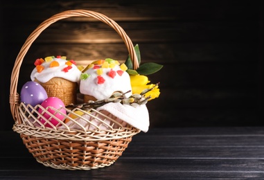 Photo of Traditional Easter cakes in wicker basket on dark background. Space for text