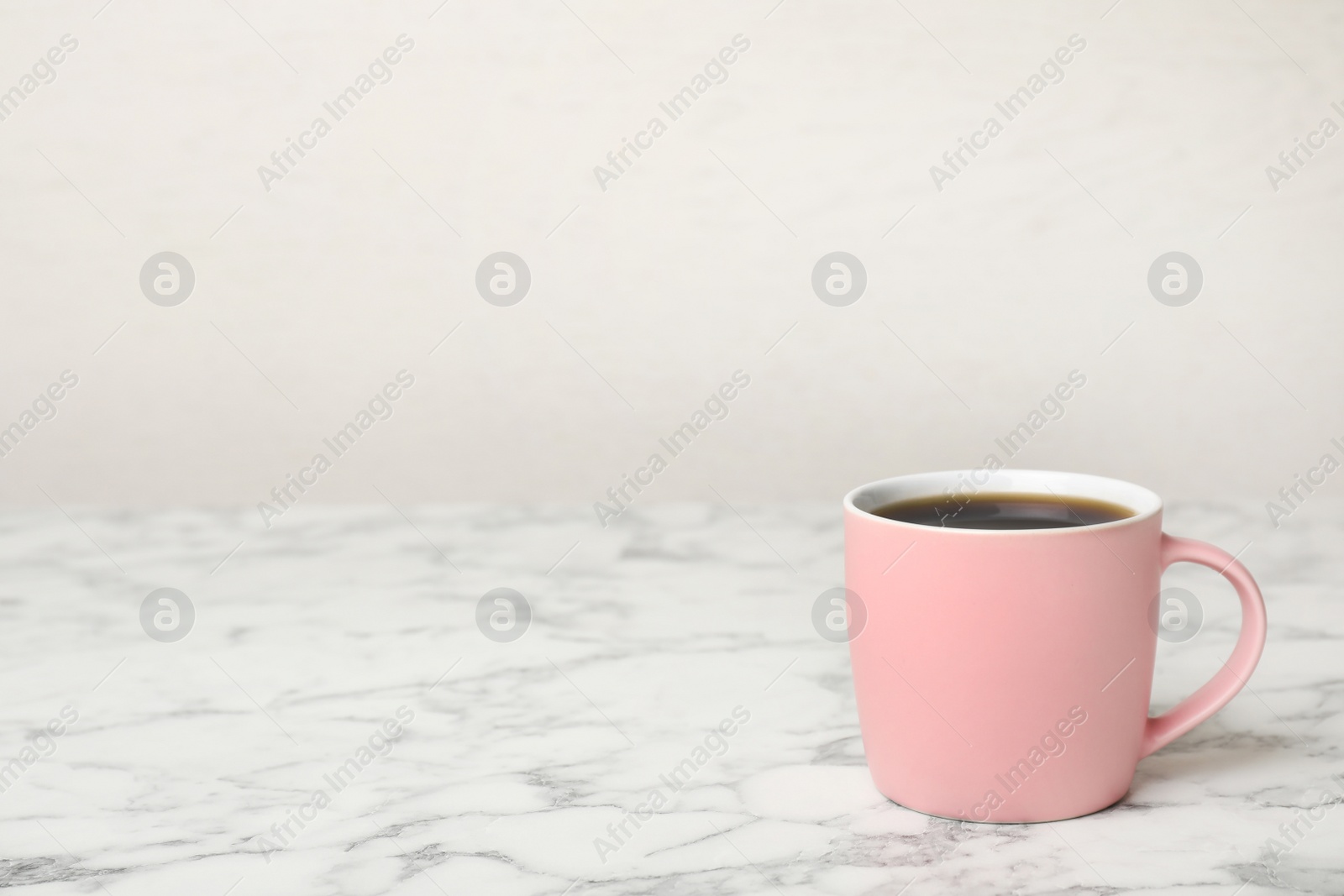 Photo of Pink ceramic cup with hot aromatic coffee on table