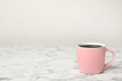 Pink ceramic cup with hot aromatic coffee on table