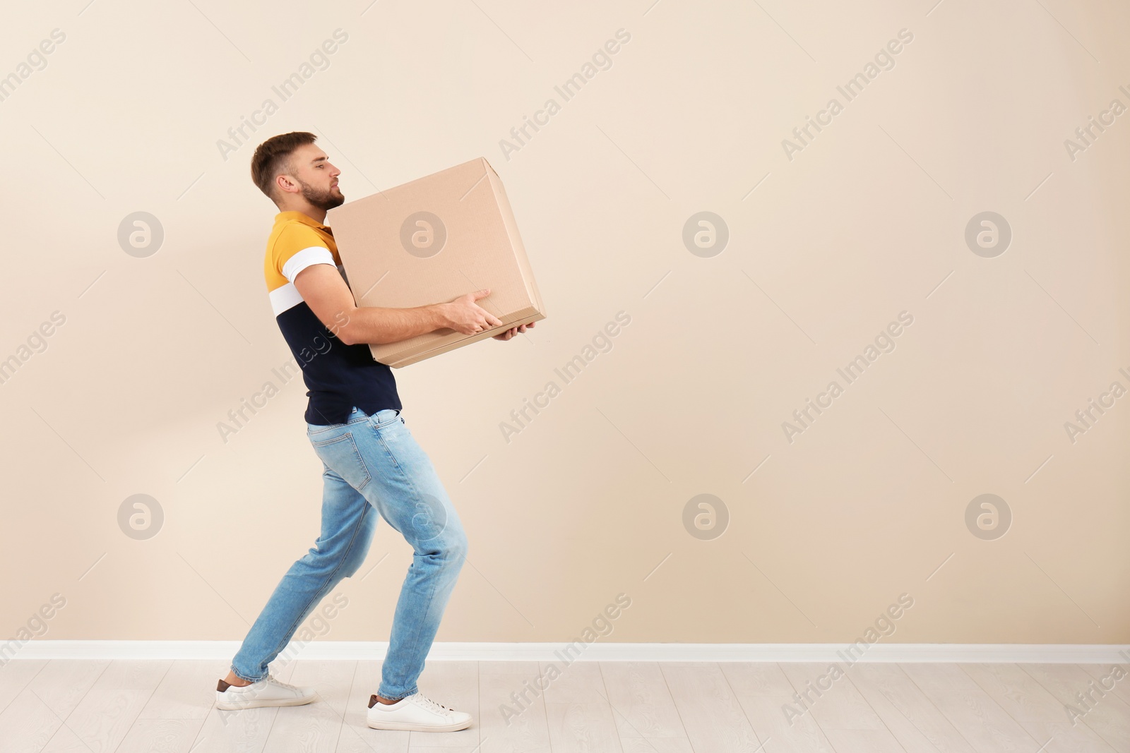 Photo of Full length portrait of young man carrying carton box near color wall. Posture concept