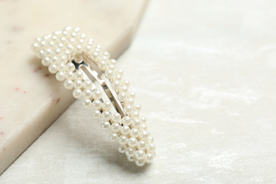 Photo of Beautiful hair clip with pearls on white table. Space for text