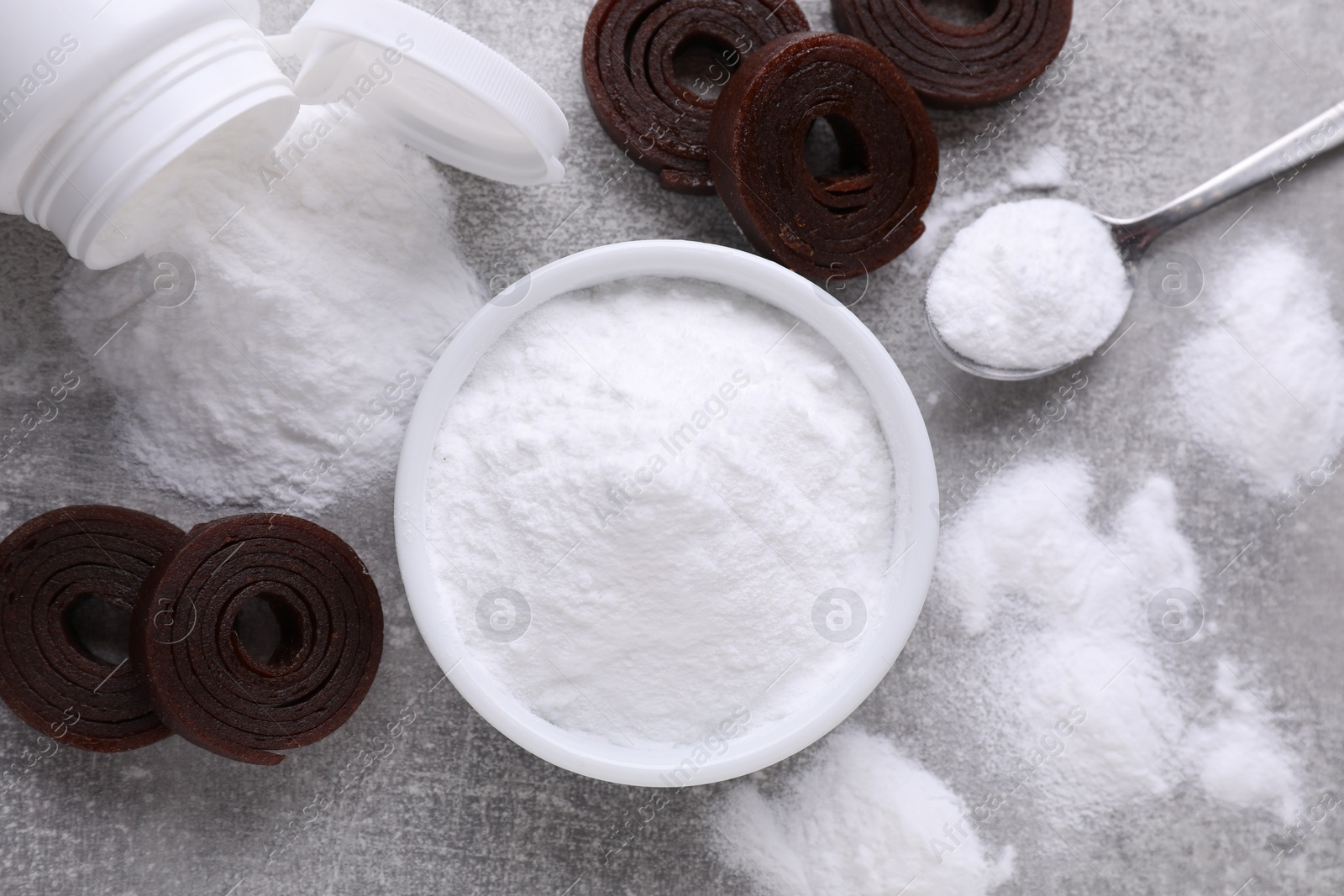 Photo of Sweet fructose powder and fruit leather rolls on light grey table, flat lay